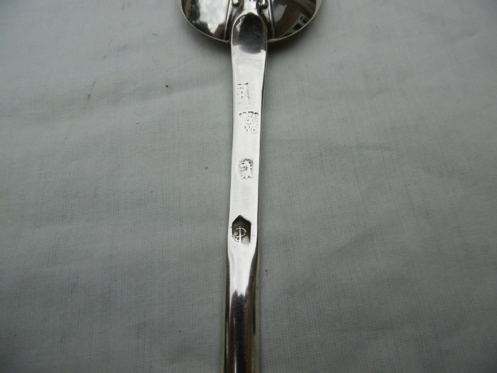 An antique Queen Anne silver marrow spoon showing an oval bowl with a rat-tail joint and a narrow scoop stem stamped with hallmarks. View III