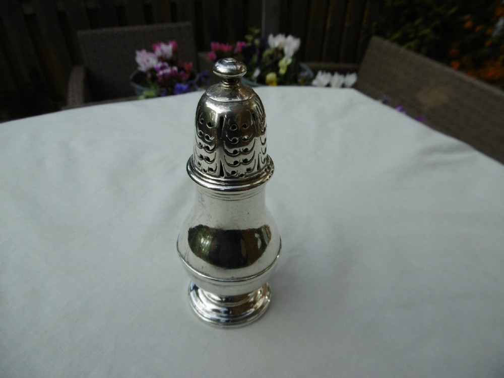 A George I sterling silver baluster-shaped caster featuring a decorative hand-pierced domed lid with a finial top.