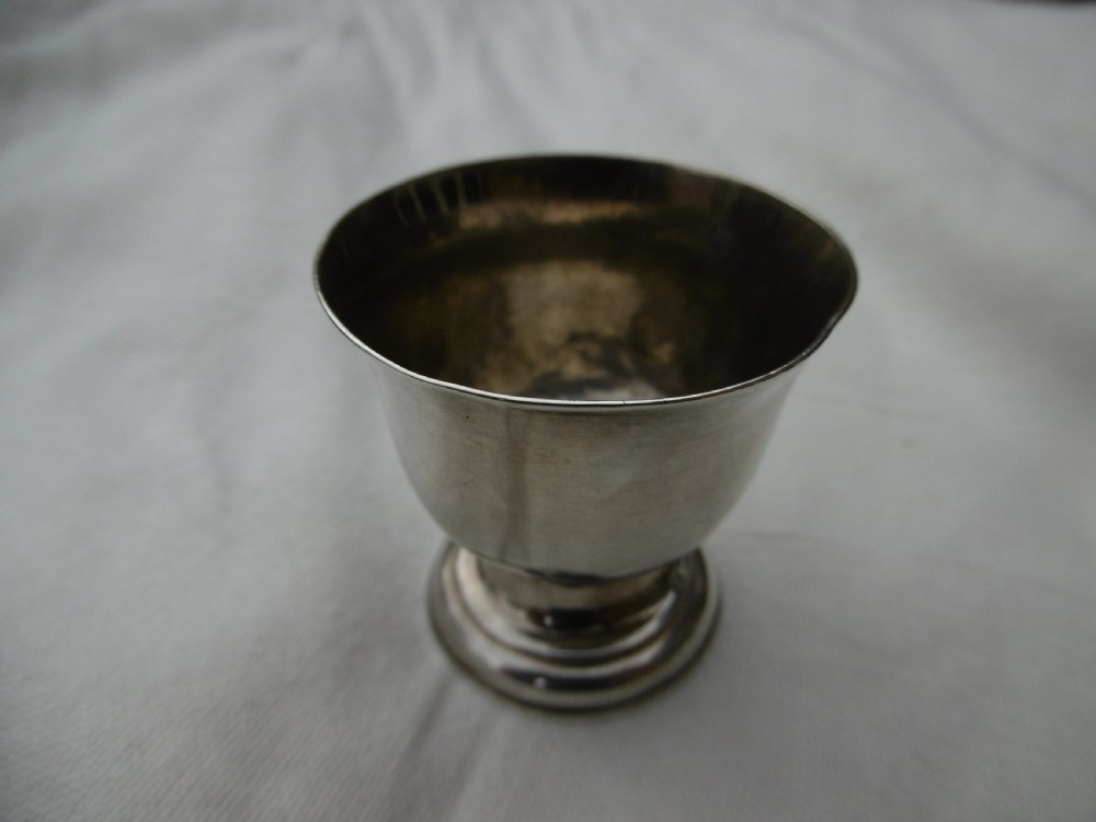A small George I sterling silver tot cup featuring a flared rim and a circular molded pedestal base.