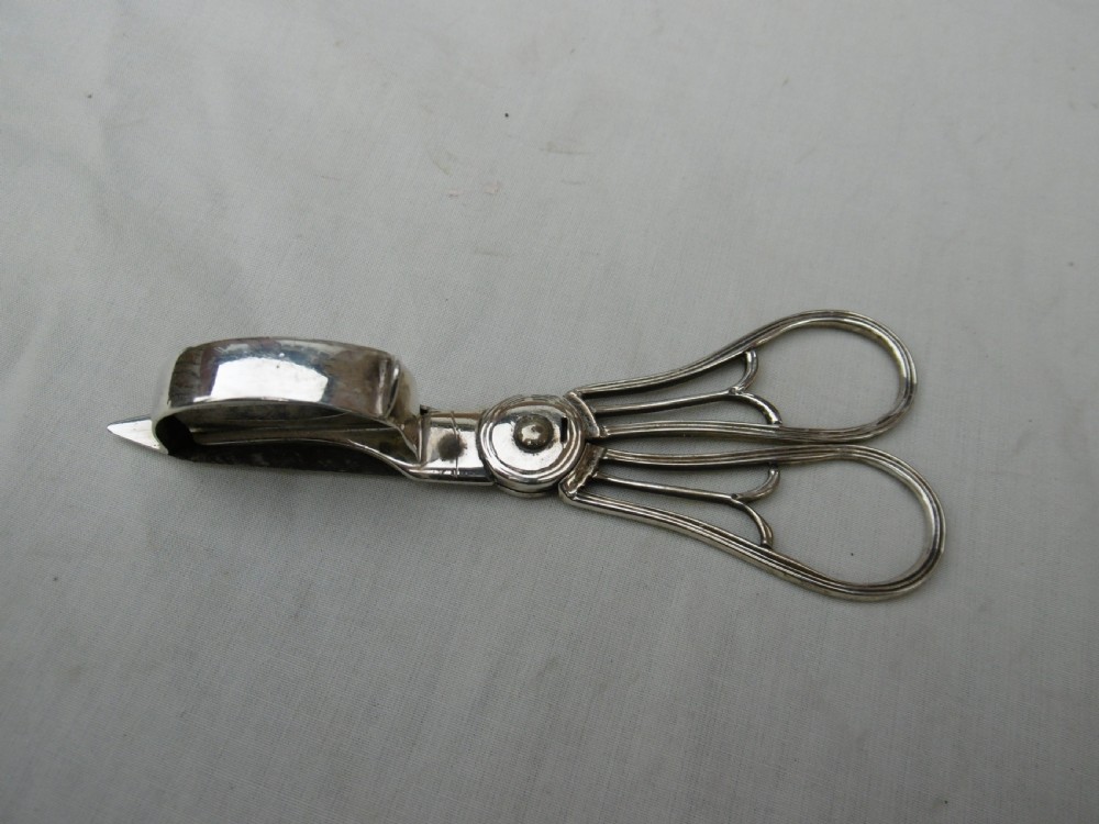 A Georgian sterling silver scissor-style candle snuffer featuring a small rectangular wick box, pointed tip, and shaped handle loops.