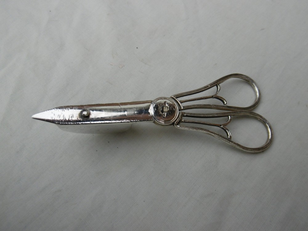 A Georgian sterling silver scissor-style candle snuffer featuring a small rectangular wick box, pointed tip, and shaped handle loops. View II