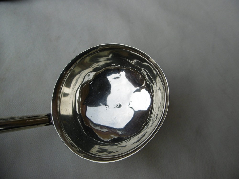 A set of six Georgian silver toddy ladles with circular bowls and dark twisted handles laid in a row. View III