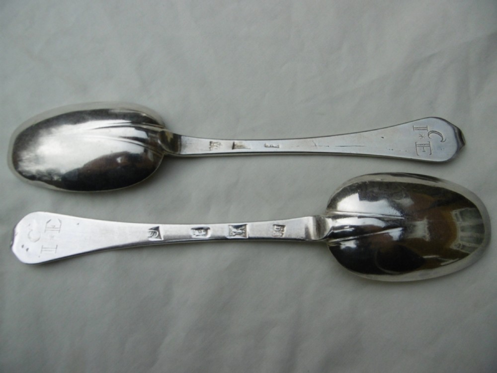 A pair of late 17th-century silver dognose tablespoons displaying rat-tail bowl supports, stem hallmarks, and engraved initials on the terminals.