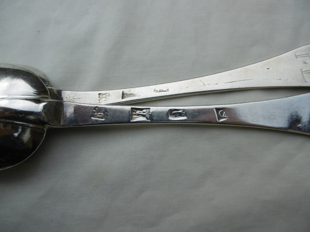 A pair of late 17th-century silver dognose tablespoons displaying rat-tail bowl supports, stem hallmarks, and engraved initials on the terminals. View II
