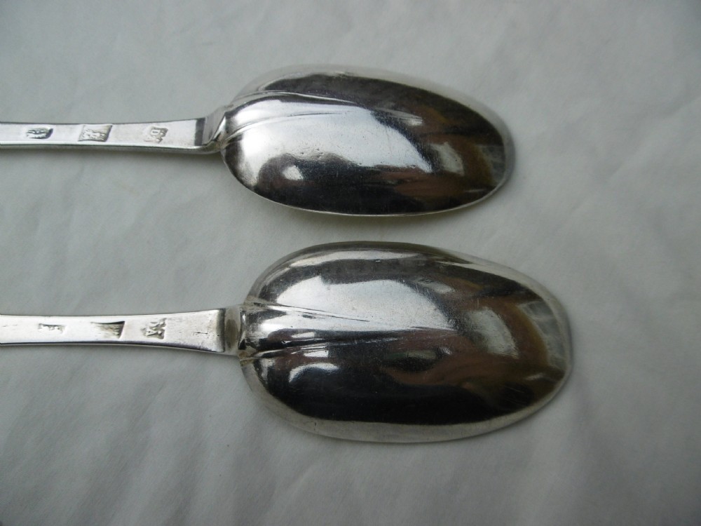 A pair of late 17th-century silver dognose tablespoons displaying rat-tail bowl supports, stem hallmarks, and engraved initials on the terminals. View V