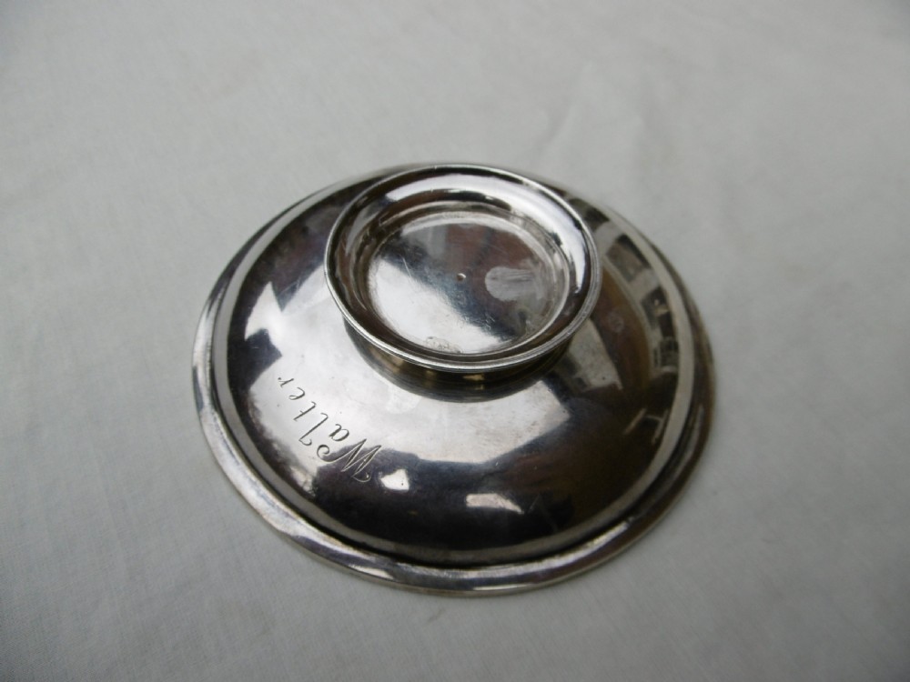 A circular Georgian sterling silver paten dish with a moulded rim resting on a short foot ring. View II