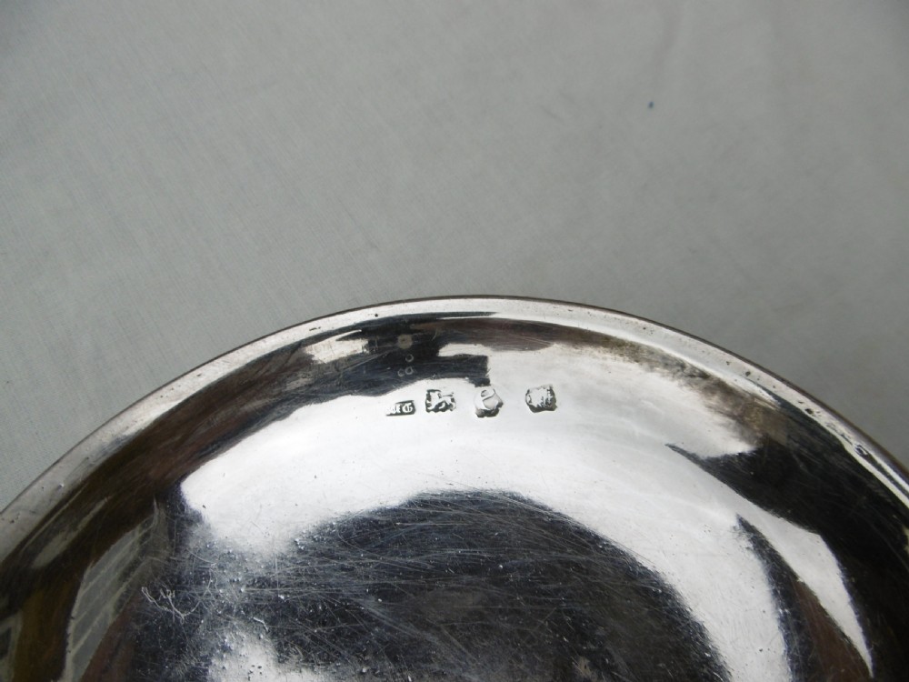 A circular Georgian sterling silver paten dish with a moulded rim resting on a short foot ring. View III