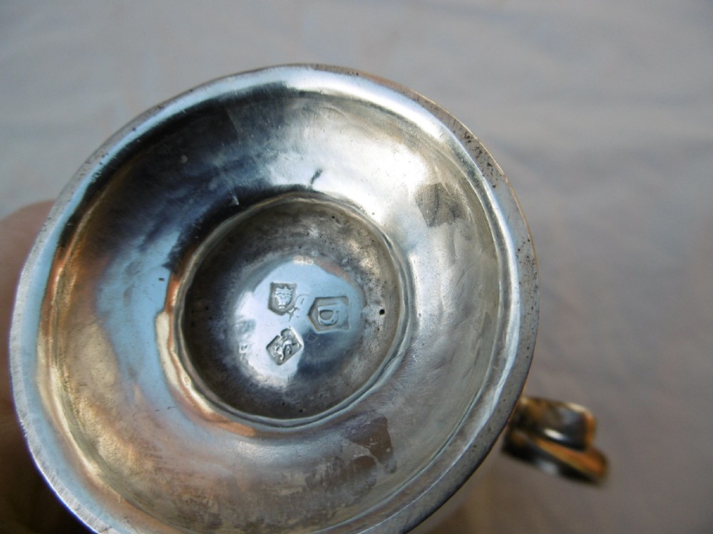 A George II sterling silver cream jug featuring a baluster body, sparrow beak spout, loop handle, and circular pedestal foot. View II