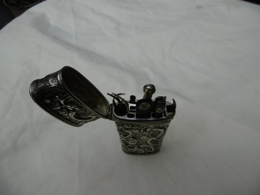 An eighteenth-century silver etui decorated with repousse relief patterns, shown with its hinged top open to reveal interior slots and fitted tools.