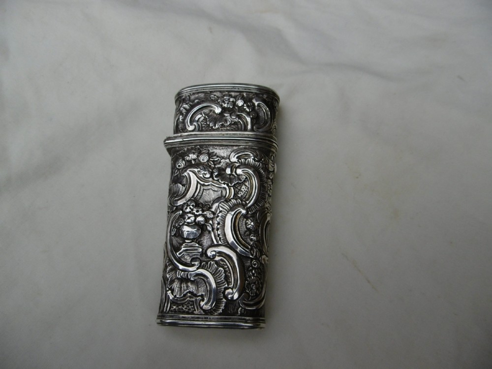 An eighteenth-century silver etui decorated with repousse relief patterns, shown with its hinged top open to reveal interior slots and fitted tools. View II