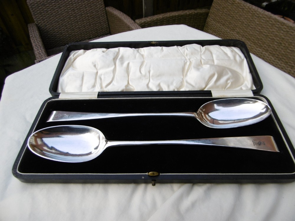 A pair of 18th-century Irish sterling silver basting spoons with hooked terminals presented inside a black velvet and silk lined case.