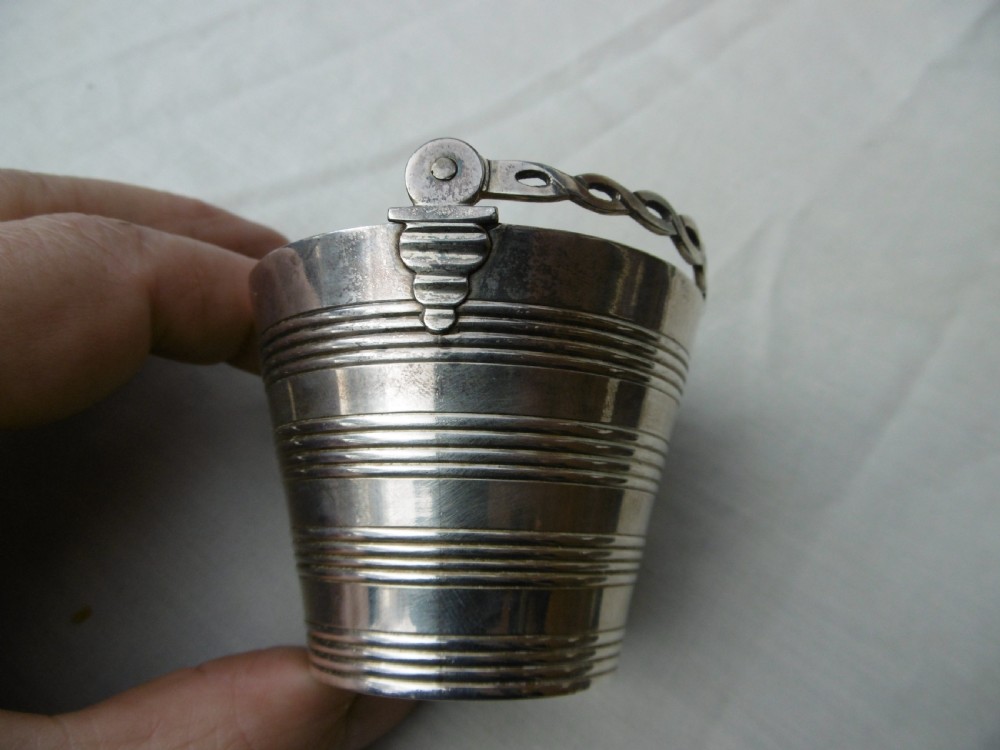 A Georgian sterling silver cream pail featuring a tapered bucket shape decorated with horizontal reeded lines and an overhead swing handle. View II