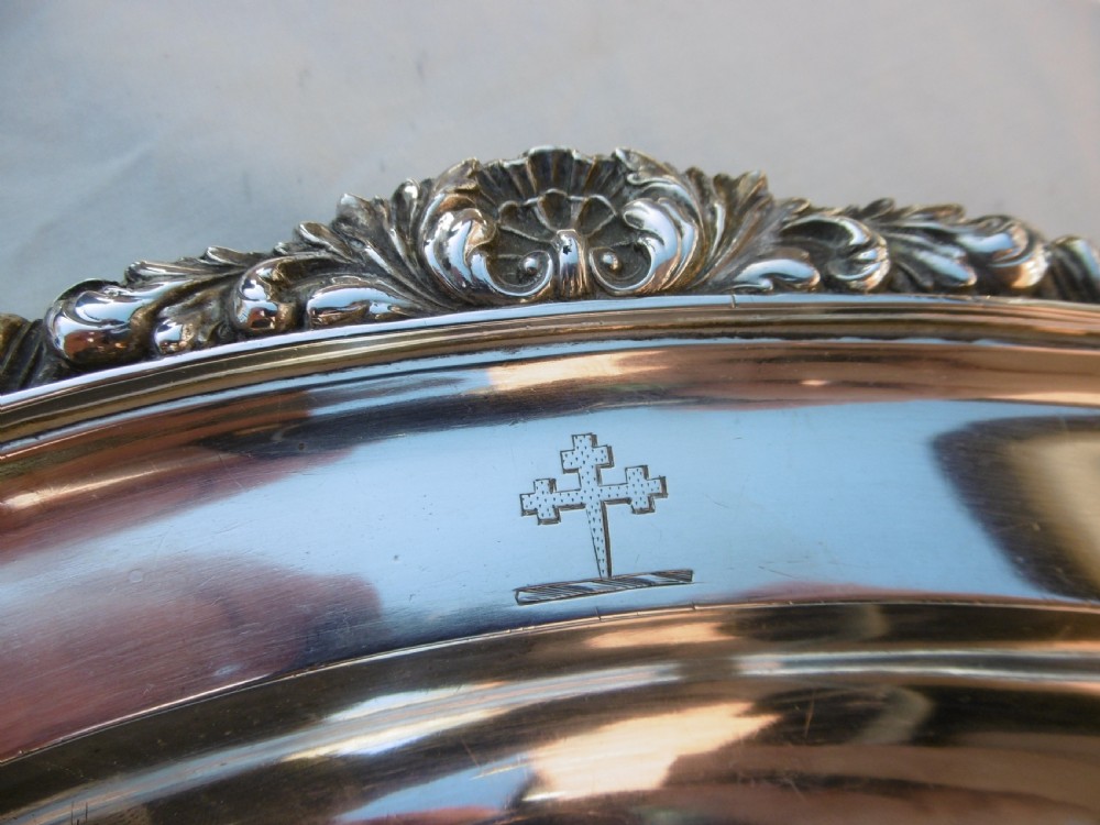 An oval Georgian sterling silver platter featuring a cast shell and gadrooned border with an engraved heraldic crest. View IV
