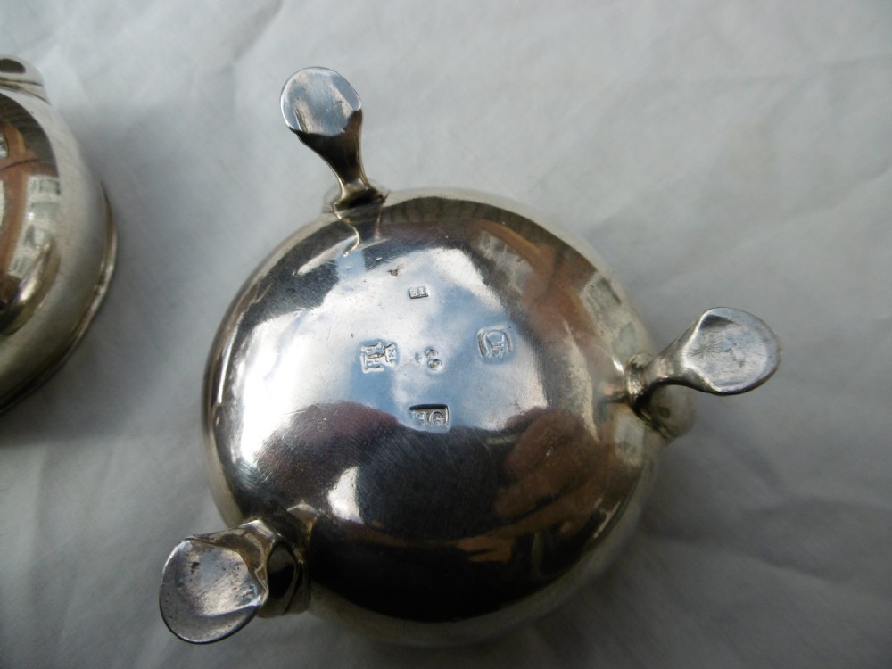 A pair of circular Scottish Georgian sterling silver open salt cellars with hoof feet alongside matching small silver salt spoons. View III