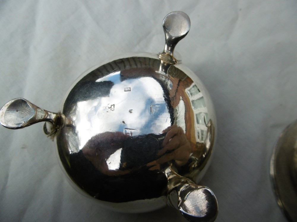 A pair of circular Scottish Georgian sterling silver open salt cellars with hoof feet alongside matching small silver salt spoons. View IV