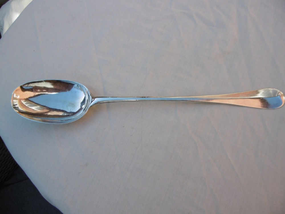 A George I Britannia standard silver basting spoon featuring a long tapered handle and an oval bowl with a rat-tail joint. View V