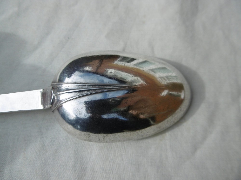 An antique silver William III trefid spoon with stamped hallmarks along the flat stem, engraved initials on the notched terminal, and a rat-tail bowl attachment. View V