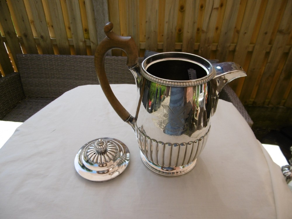 A Georgian silver coffee pot featuring fluted lower body detailing, an engraved crest, and a carved wooden handle. View III