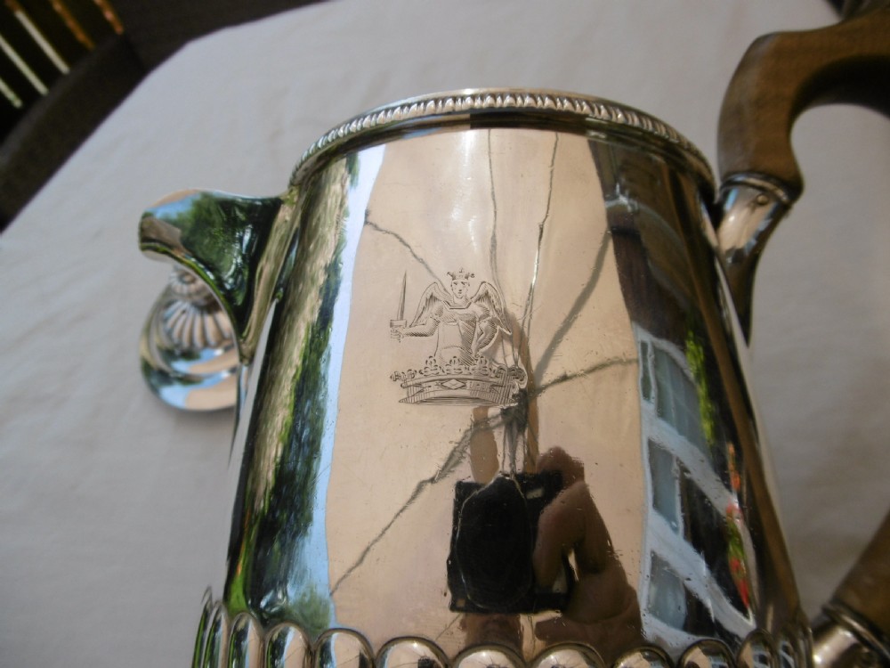 A Georgian silver coffee pot featuring fluted lower body detailing, an engraved crest, and a carved wooden handle. View VI