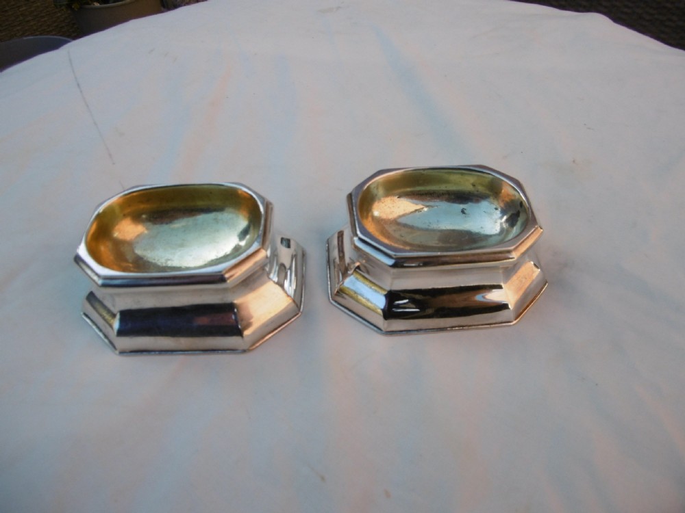 A pair of 18th-century octagonal sterling silver trencher salts with gilt-lined interior bowls.