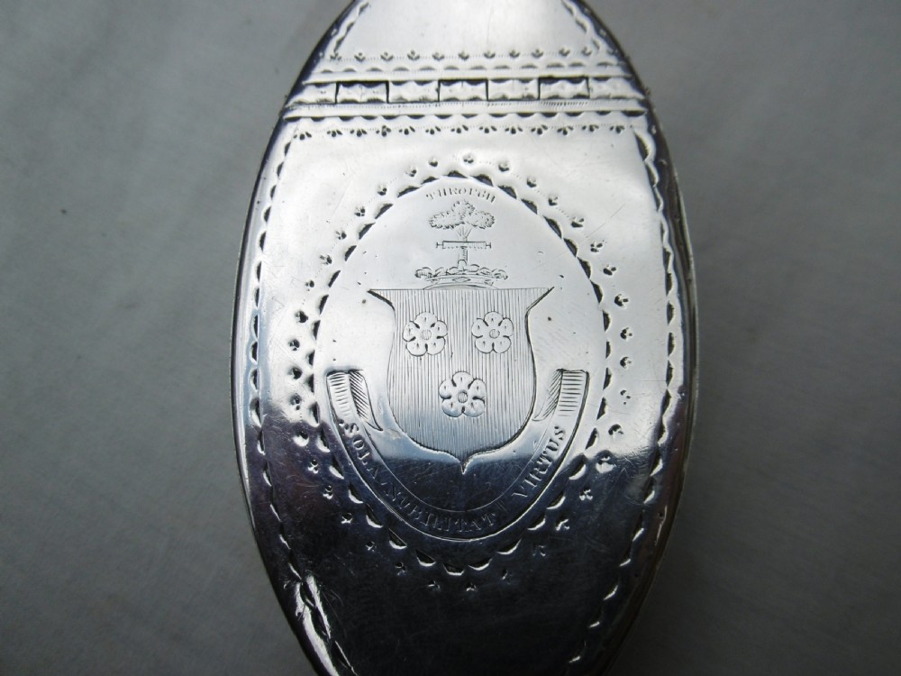An oval Georgian silver snuff box decorated with bright-cut engraving and an armorial coat of arms. View II
