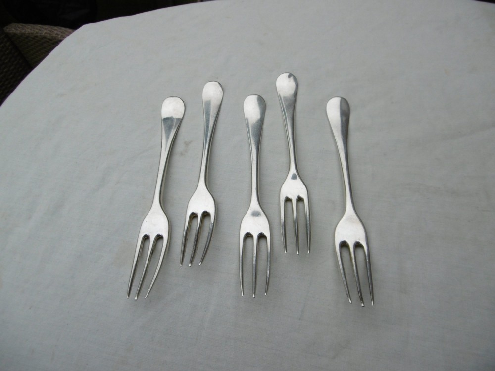 A set of five mid-eighteenth-century sterling silver dessert forks with three prongs and slender Hanoverian-style stems.