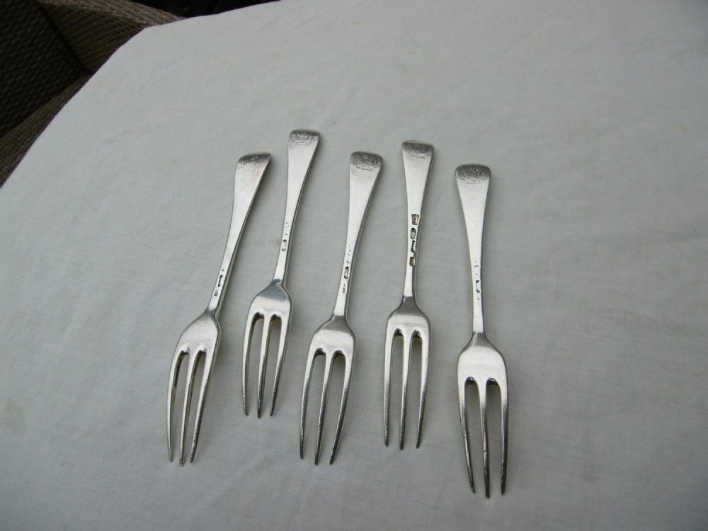 A set of five mid-eighteenth-century sterling silver dessert forks with three prongs and slender Hanoverian-style stems. View II
