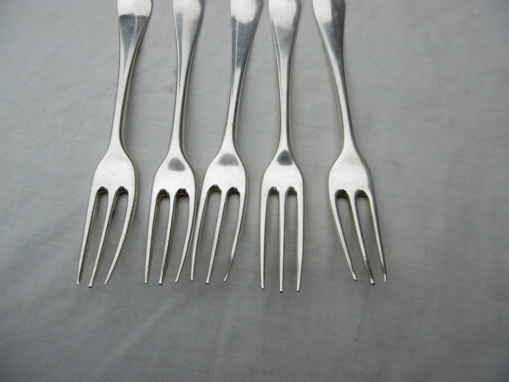 A set of five mid-eighteenth-century sterling silver dessert forks with three prongs and slender Hanoverian-style stems. View VI