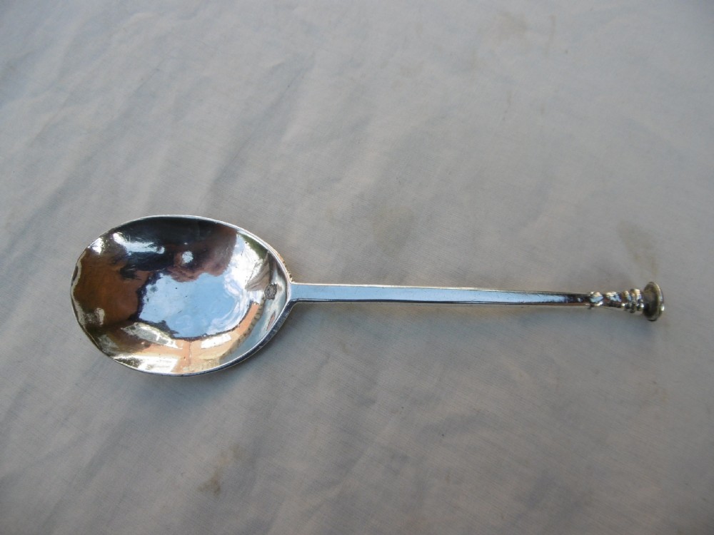 A sterling silver spoon featuring a wide fig-shaped bowl, a slim straight stem, and a rounded seal top terminal.