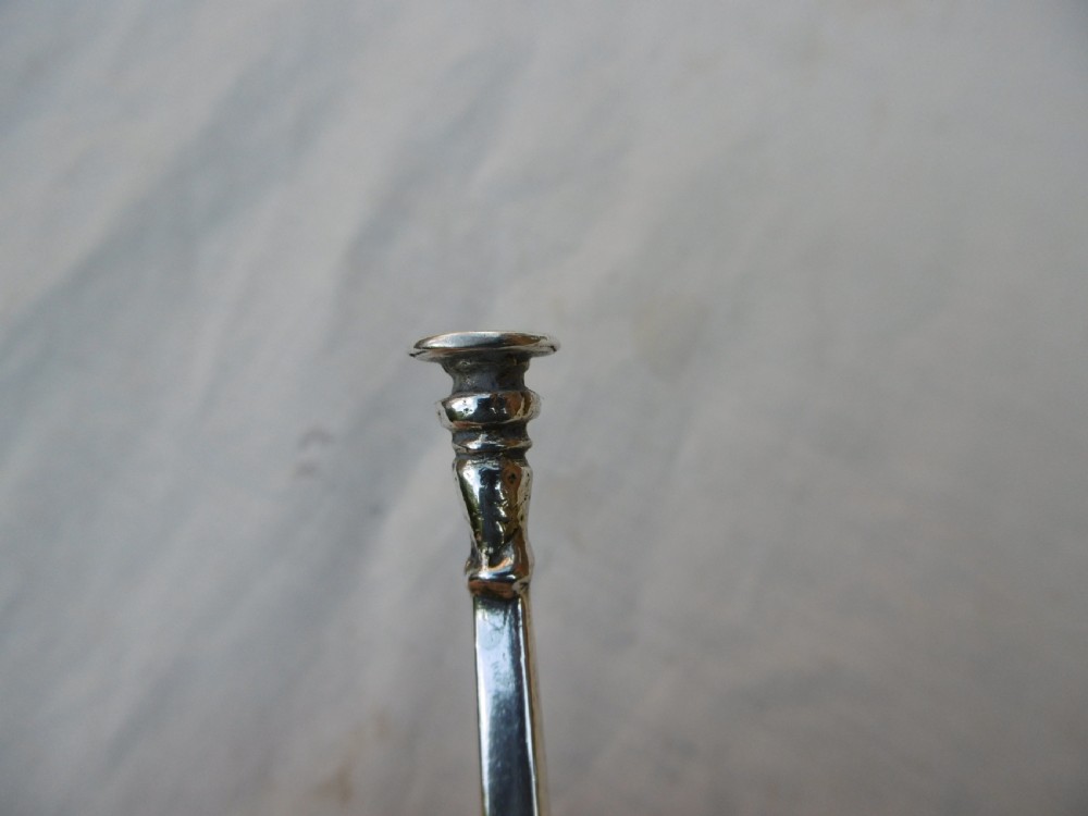 A sterling silver spoon featuring a wide fig-shaped bowl, a slim straight stem, and a rounded seal top terminal. View IV