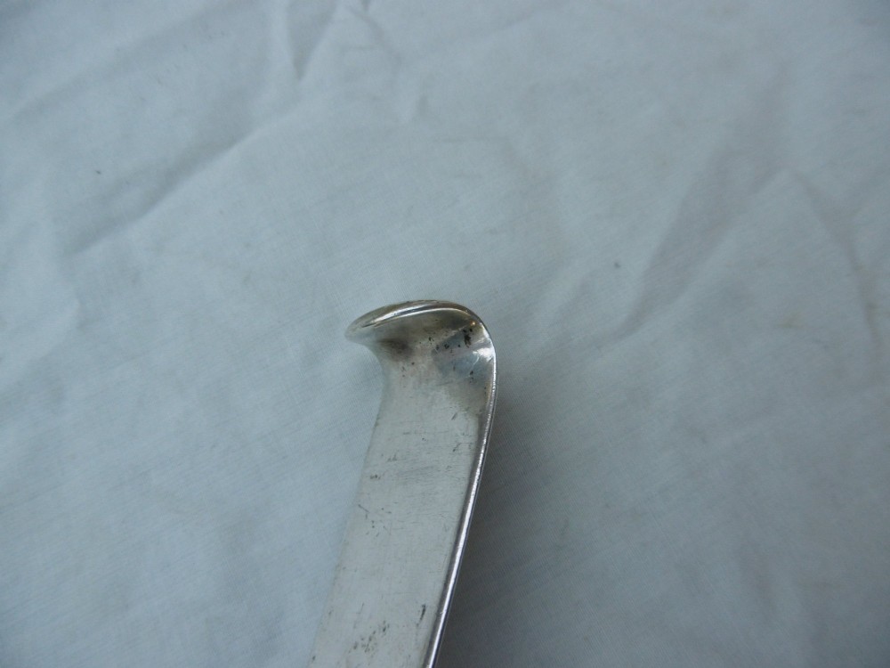 An 18th-century Irish Georgian sterling silver basting spoon featuring a tapered stem with an engraved family crest and a distinctive hooked handle terminal. View IV