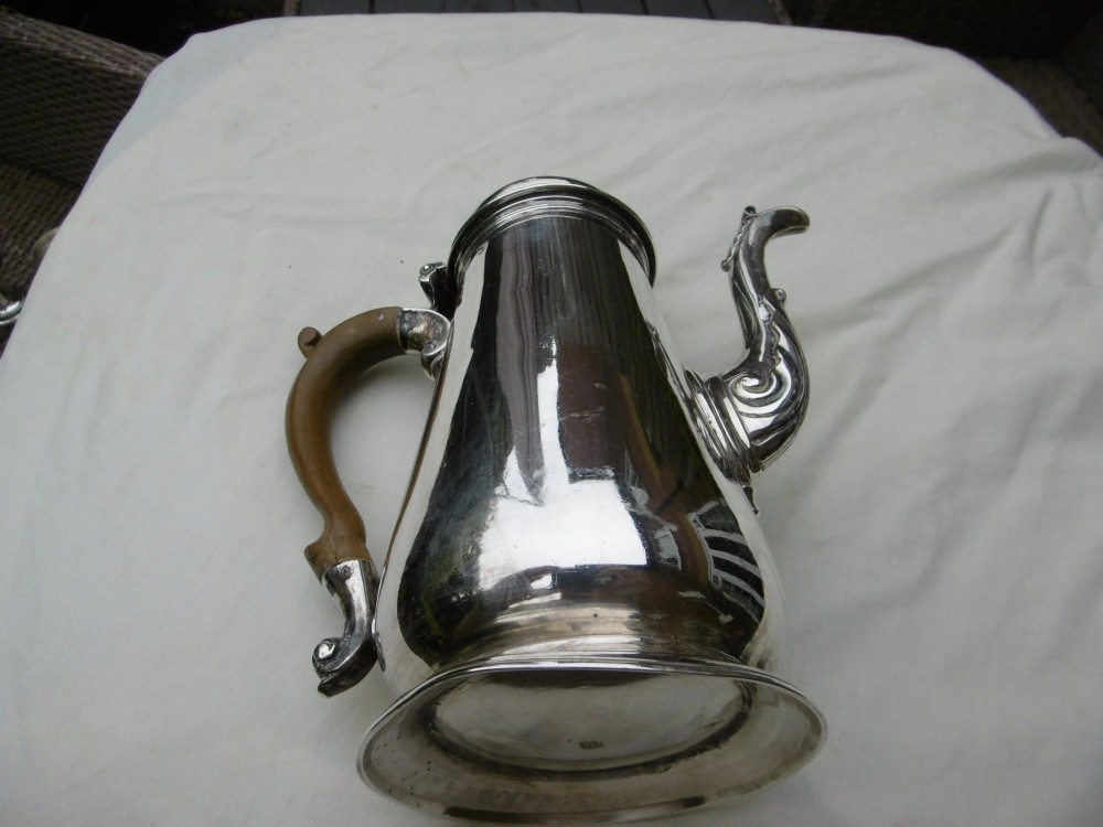 A George II sterling silver coffee pot with a tapered body, domed lid, decorative cast spout, and a curved wooden handle. View II