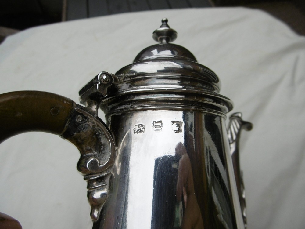 A George II sterling silver coffee pot with a tapered body, domed lid, decorative cast spout, and a curved wooden handle. View III