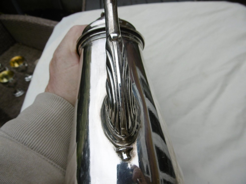 A George II sterling silver coffee pot with a tapered body, domed lid, decorative cast spout, and a curved wooden handle. View VI