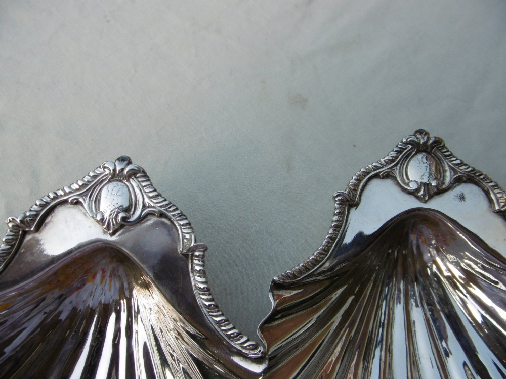 A pair of 18th-century sterling silver butter dishes shaped like scallop shells with fluted interiors and engraved handles. View II