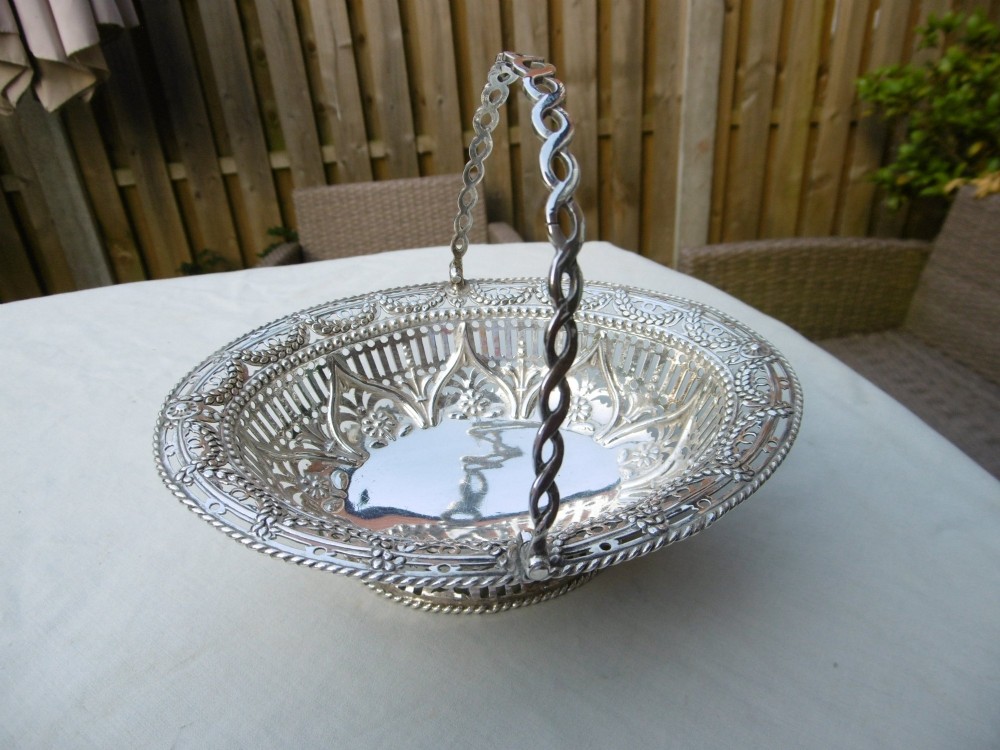 An oval 18th-century sterling silver basket featuring pierced openwork, an embossed rim, and a twisted swing handle.