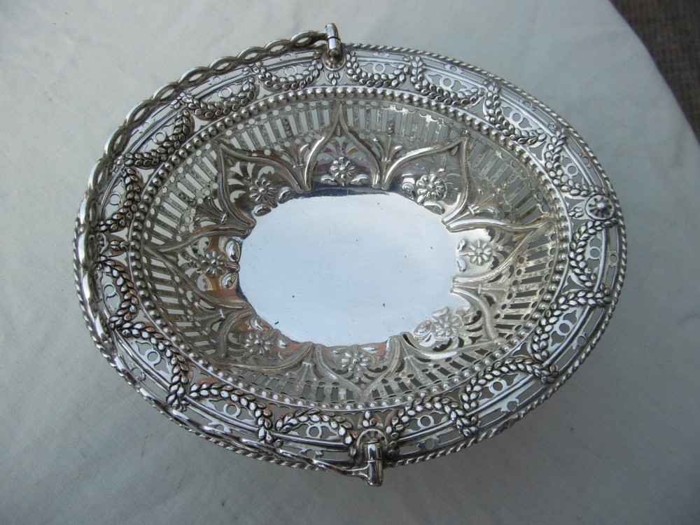 An oval 18th-century sterling silver basket featuring pierced openwork, an embossed rim, and a twisted swing handle. View II