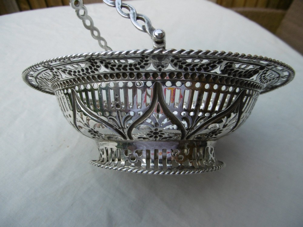 An oval 18th-century sterling silver basket featuring pierced openwork, an embossed rim, and a twisted swing handle. View IV