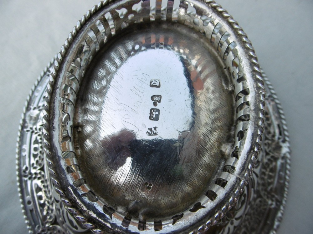 An oval 18th-century sterling silver basket featuring pierced openwork, an embossed rim, and a twisted swing handle. View V