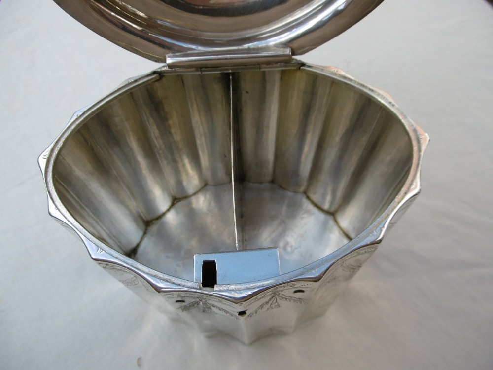 A George III fluted sterling silver tea caddy featuring bright-cut engraved drapery swags, a central keyhole, and a hinged lid topped with a turned finial. View VIII