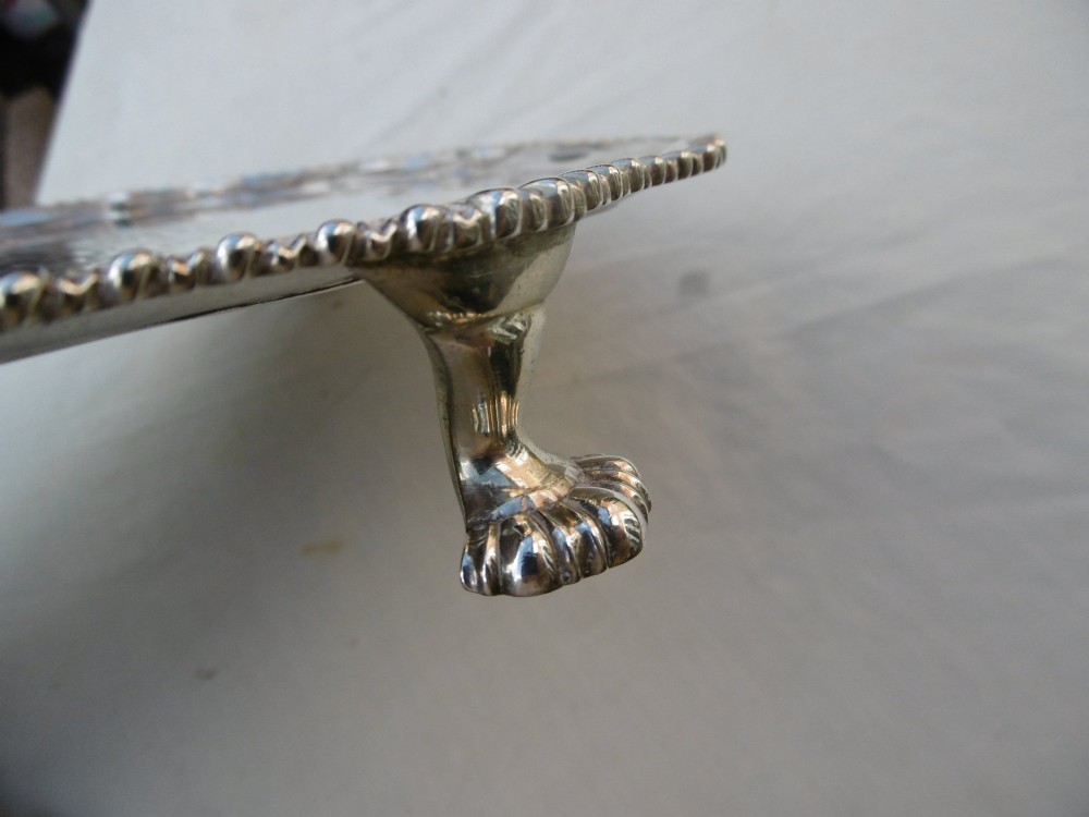 A circular Georgian sterling silver salver featuring a scalloped gadrooned rim and a central armorial crest engraving. View II
