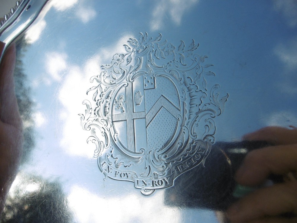 A circular Georgian sterling silver salver featuring a scalloped gadrooned rim and a central armorial crest engraving. View V