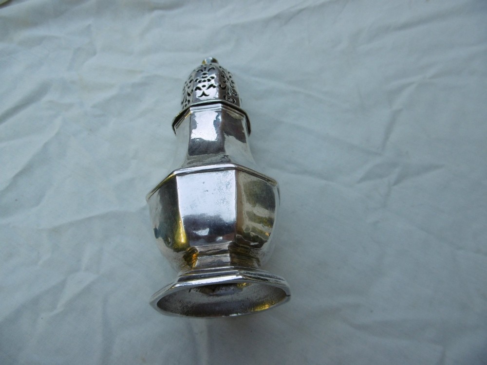 An 18th-century octagonal sterling silver sugar caster featuring a baluster-shaped body, moulded foot, and intricate pierced dome lid topped with a finial. View V