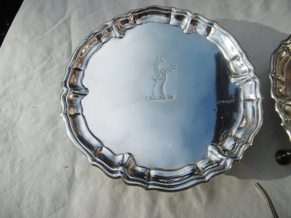 A pair of round George II sterling silver waiters with piecrust borders, resting on small feet, each central panel engraved with a stag crest. View II
