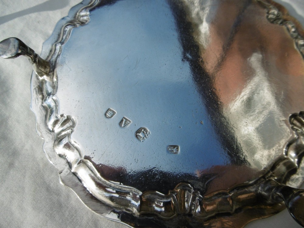A pair of round George II sterling silver waiters with piecrust borders, resting on small feet, each central panel engraved with a stag crest. View V