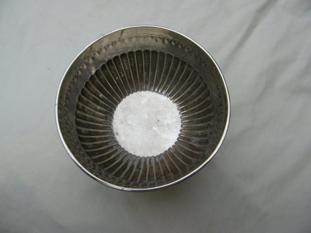 A George III sterling silver footed bowl featuring a fluted lower body, an engraved foliate upper border, and a stepped circular base. View II