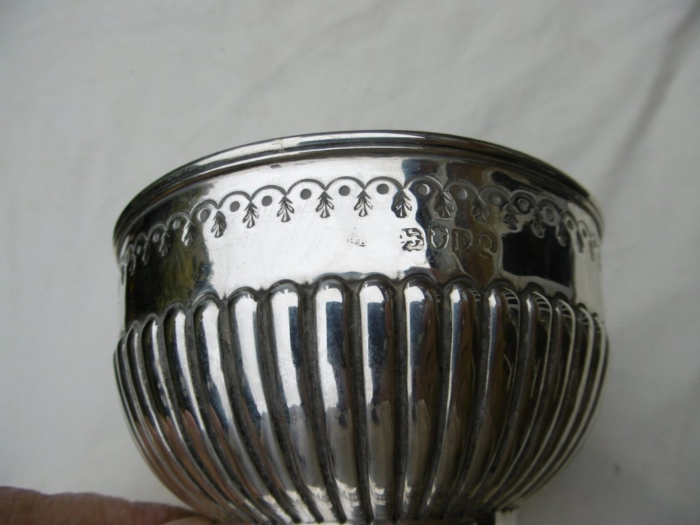 A George III sterling silver footed bowl featuring a fluted lower body, an engraved foliate upper border, and a stepped circular base. View IV