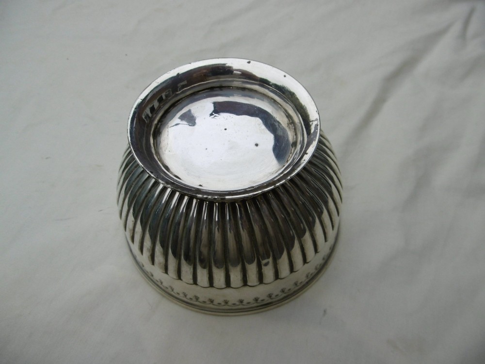 A George III sterling silver footed bowl featuring a fluted lower body, an engraved foliate upper border, and a stepped circular base. View V