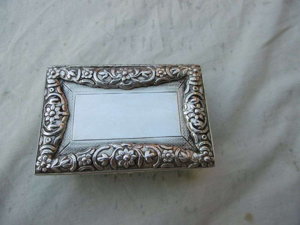 A rectangular William IV sterling silver table snuff box featuring heavily chased floral borders and an engine-turned lid with a plain central cartouche. View VI