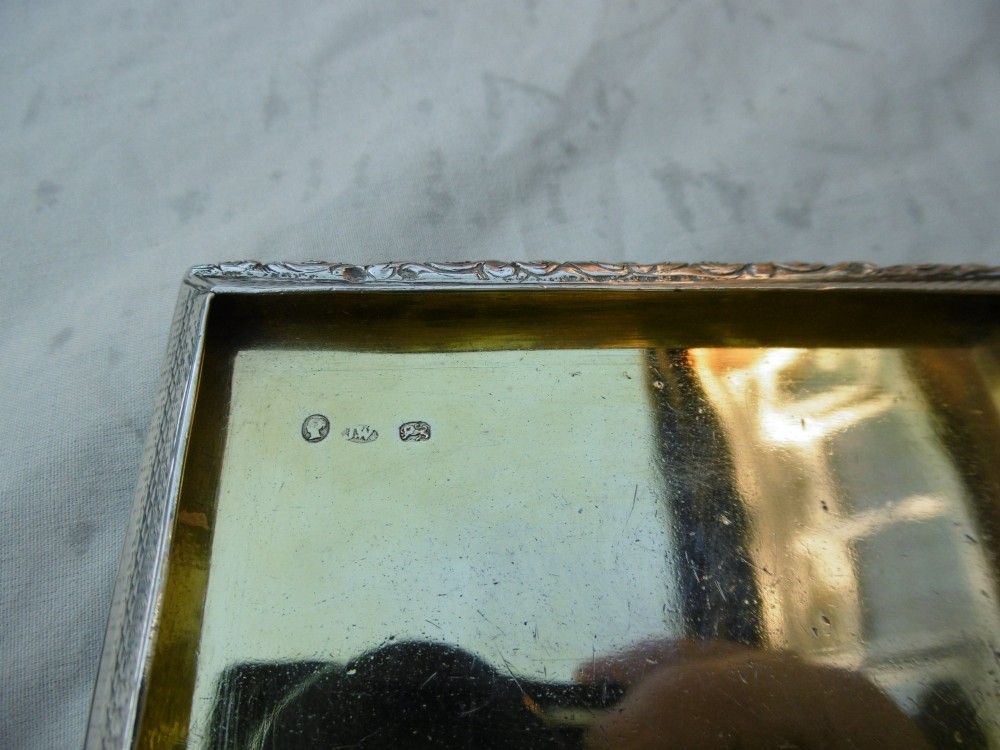 A rectangular William IV sterling silver table snuff box featuring heavily chased floral borders and an engine-turned lid with a plain central cartouche. View VII
